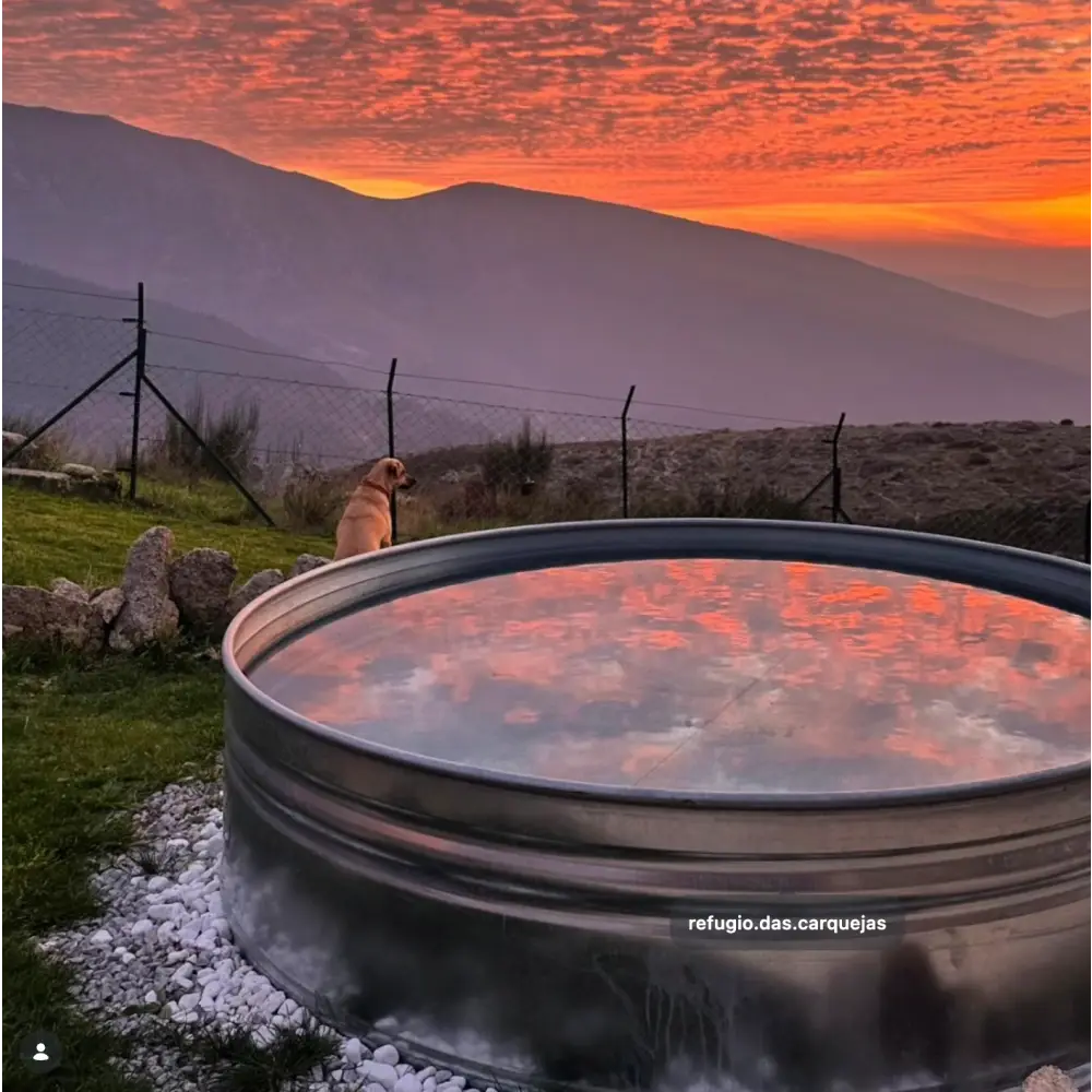 A large round galvanized steel stock tank pool on a farm with sunset sky and mountain view in america 